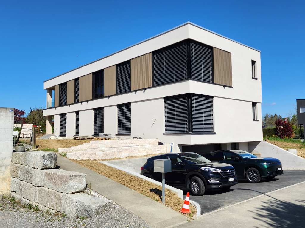 Zeitgenössisches Gebäude mit klaren Linien und großen Fenstern in hellem Design.